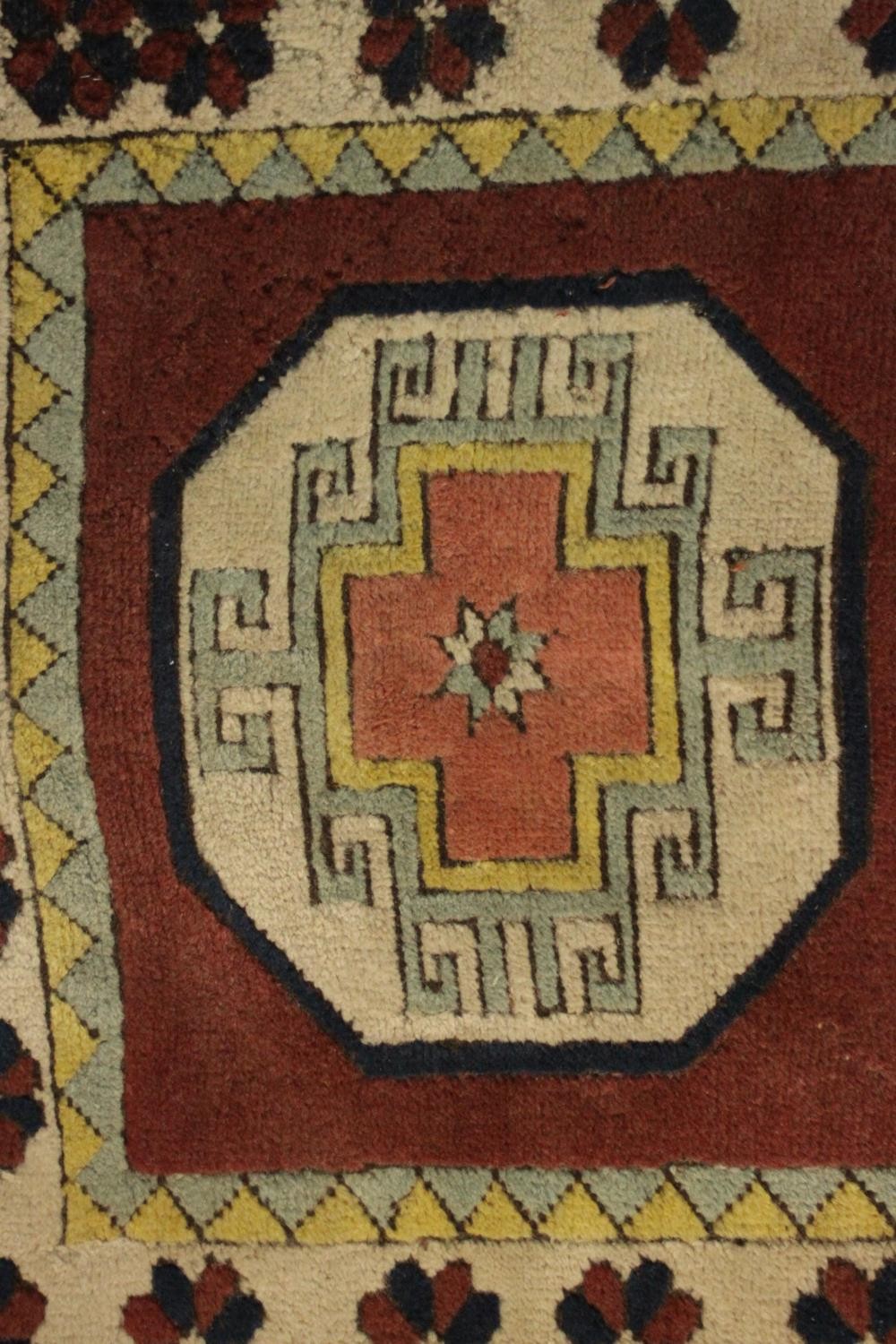 A Turkish runner with repeating lozenge medallions within a flowerhead border. L.310 W.30cm. - Image 5 of 7