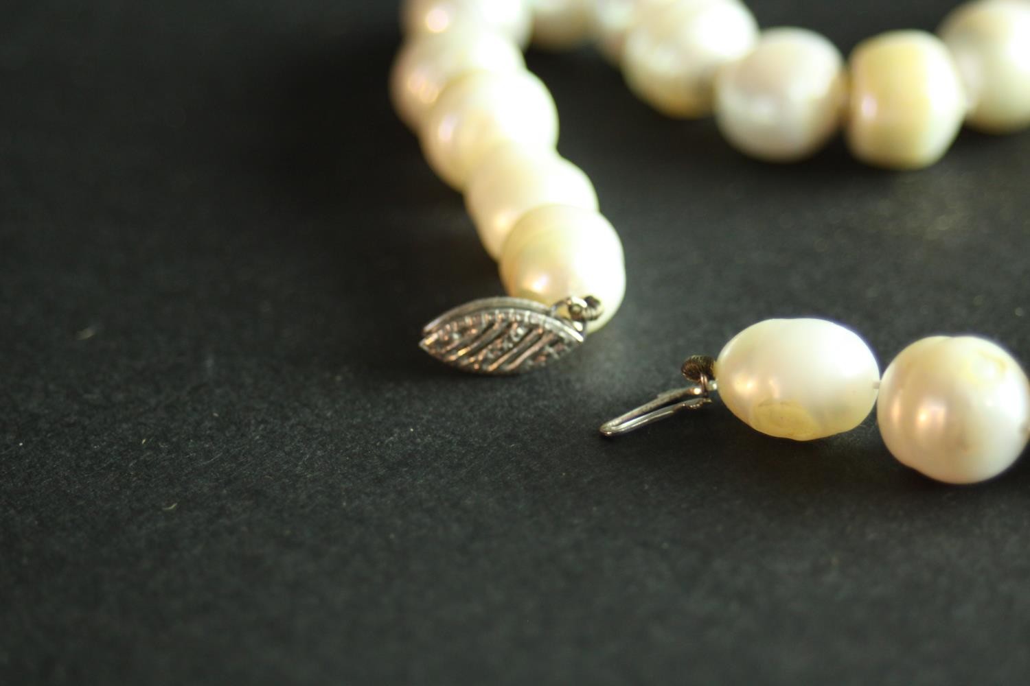 A string of vintage knotted baroque cultured pearls with a silver hook and push clasp. H.7 W.10 cm. - Image 4 of 6