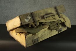 A canvas suitcase full of various items of military uniform and a silk and velvet ladies dress