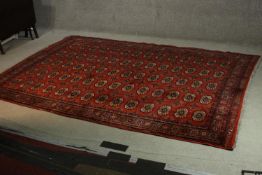 A Bokhara motif carpet with repeating gul medallions on a burgundy ground. L.260 W.190cm.