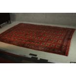 A Bokhara motif carpet with repeating gul medallions on a burgundy ground. L.260 W.190cm.