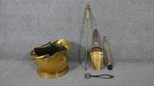 An early 20th century hammered brass helmet shaped coal scuttle and fire irons. H.35 W.37 D.30cm (