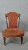 A Victorian walnut framed button backed nursing chair on tapering fluted supports.
