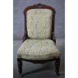 A 19th century carved walnut framed nursing chair in floral upholstery on turned tapering supports.