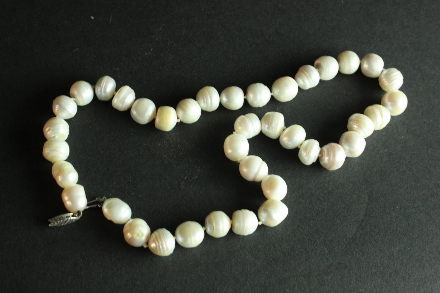 A string of vintage knotted baroque cultured pearls with a silver hook and push clasp. H.7 W.10 cm. - Image 3 of 6