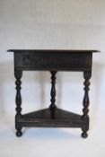 A late 19th century Jacobean style oak corner table on turned tapering supports united by undertier.