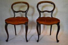 A pair of Victorian rosewood balloon back dining chairs with deep buttoned stuffover seats on shaped