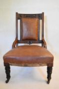 A late Victorian carved mahogany nursing chair in faux leather upholstery. H.95 W.63 D.63cm
