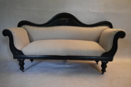 A Victorian ebonised scroll end sofa reupholstered in piped calico on turned tapering supports. H.