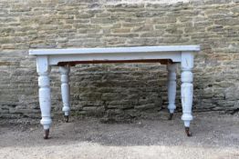 A Victorian distressed painted kitchen dining table on turned tapering supports terminating in