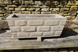 A reconstituted stone garden planter with brickwork relief pattern.