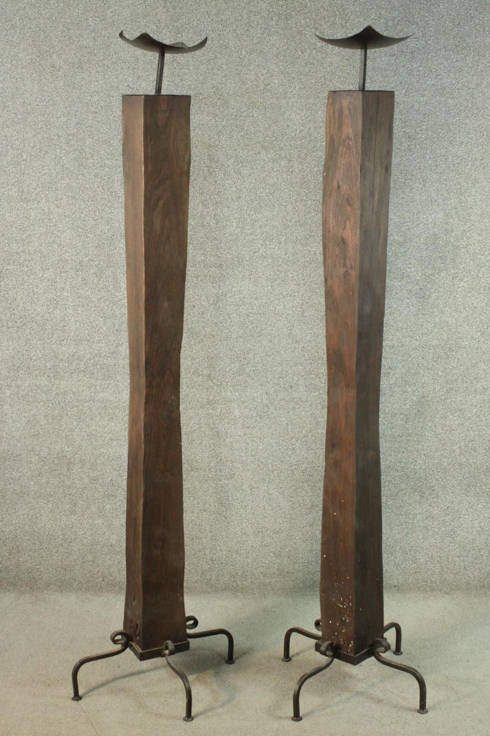 A pair of large Oriental style hardwood and wrought iron floor standing candlesticks on four prong