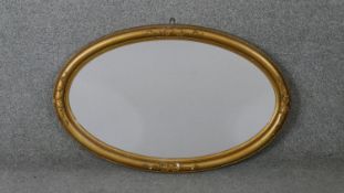 A C.1900 oval wall mirror in gilt ribbon and beaded gesso frame. H.50 W.78cm