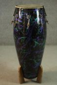 A purple and green glitter abstract design fibre glass Conga drum on wooden stand. H.92 W.31cm.