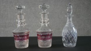 A pair of early 20th century Bohemian cut crystal decanters with painted ruby central bands engraved