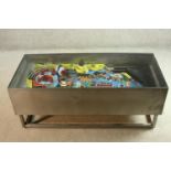 A contemporary metal framed coffee table with the major section of a vintage pinball table to the