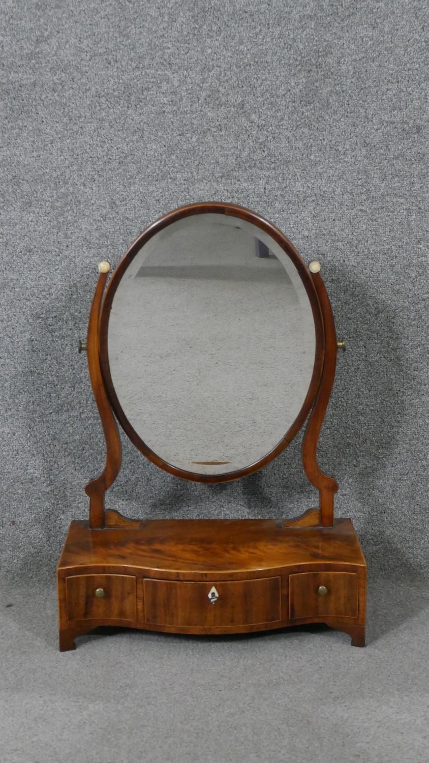 A Georgian mahogany and satinwood strung serpentine fronted swing toilet mirror. H.60 W.42 D.19cm