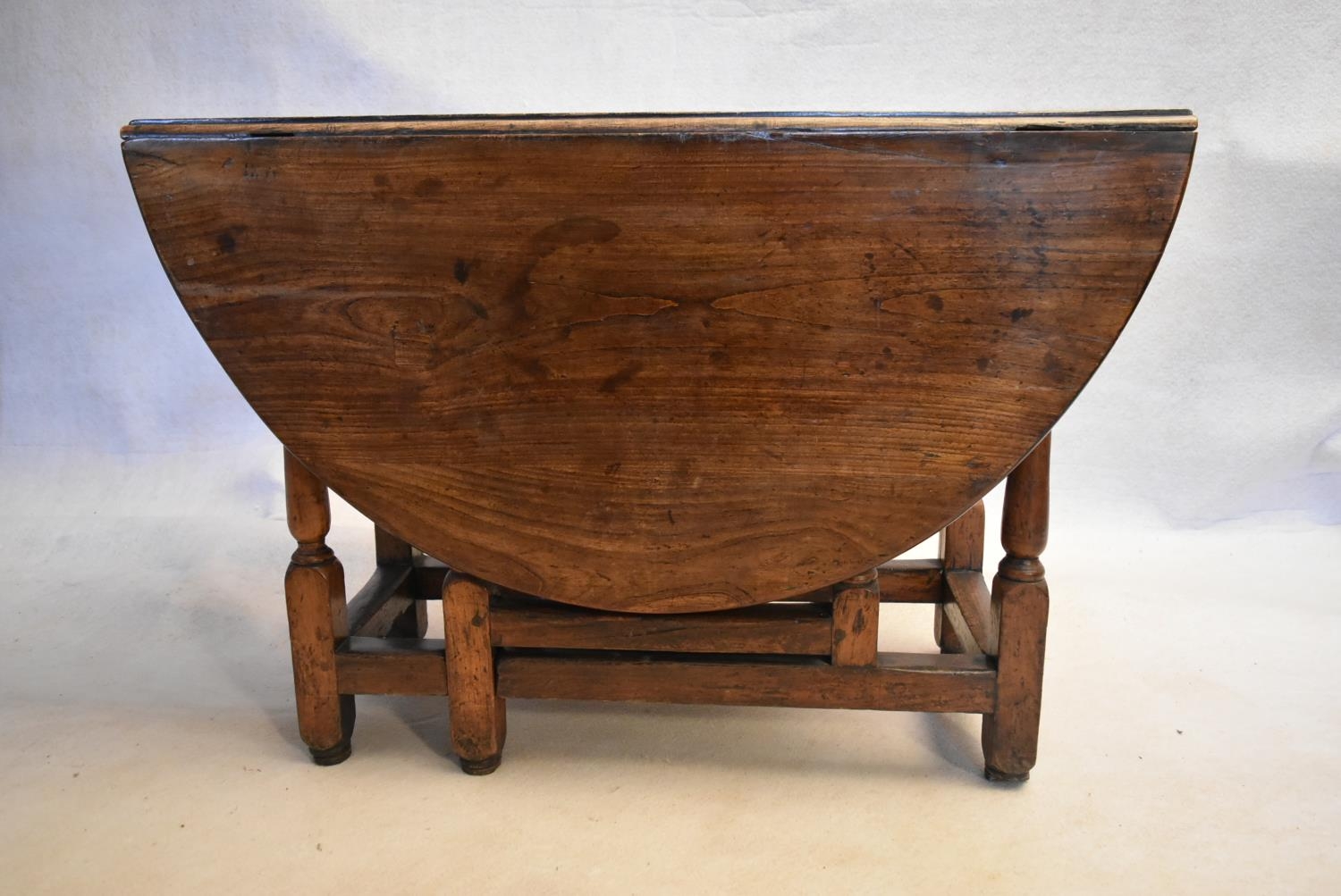 An 18th century country oak gateleg dining table with frieze drawer above turned stretchered