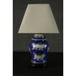 A Chinese style blue and white ceramic lidded urn vase converted into a table lamp. Decorated with