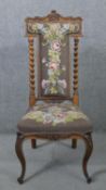 A Victorian carved rosewood prie dieu chair with barleytwist pilasters and floral tapestry