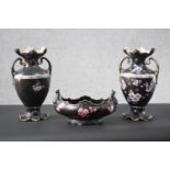 A pair of Victorian black glaze flower design twin handled vases with gilded rims along with a