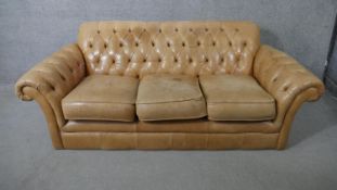 A Thomas Lloyd sofa in deep buttoned leather upholstery and the matching footstool. H.73 W.197 D.