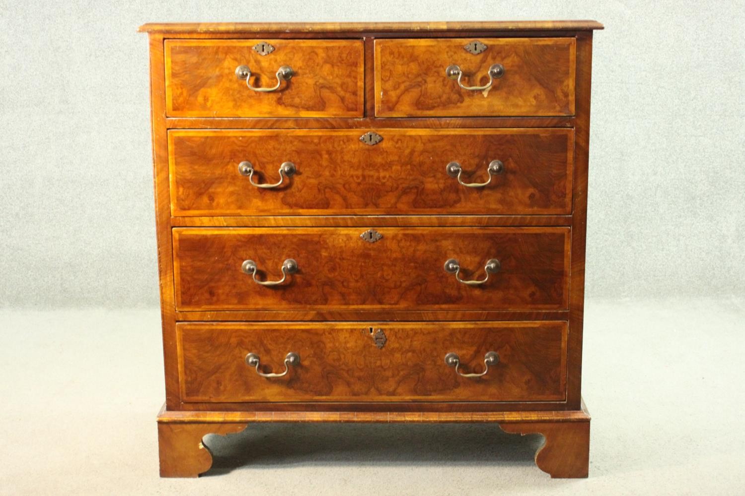 A 19th century early Georgian style walnut, crossbanded and featherbanded chest of drawers with