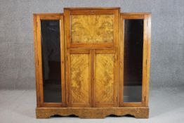 An Art Deco figured walnut bureau cabinet with a fall front enclosing a fitted interior, over a pair