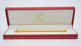 A red leather cased Le Must de Cartier "Trinity" ballpoint pen, gold-plated. Marked Cartier, Paris