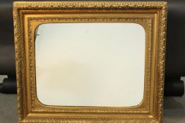 An early 20th century carved giltwood and gesso framed wall mirror. The frame decorated with