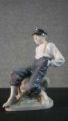 A Royal Copenhagen porcelain figure of a boy on a rock. Stamped, signed and numbered to the base.