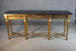 A long giltwood console table, with a rectangular black marble top, on fluted legs, joined by X
