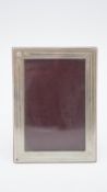 A boxed Cartier cherry wood backed easel silver photo frame with screw motifs to the corners. Signed