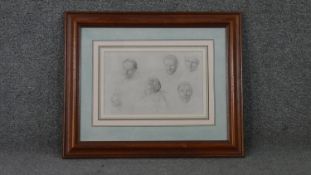 A framed and glazed print of a pencil drawing with various studies of male faces.