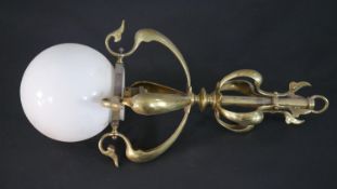 An Art Nouveau brass foliate form ceiling light with white milk glass globe shade. H.48 W.16cm