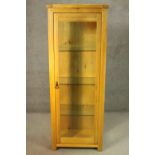A contemporary honey oak display cabinet, with glazed door and sides, enclosing glass shelves. H.180