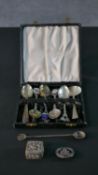 A boxed collection of six mixed silver spoons, some with enamel detailing along with a silver