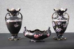 A pair of Victorian black glaze flower design twin handled vases with gilded rims along with a