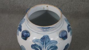 Two large Chinese blue and white lidded urns. One decorated with bok choy leaves and a foo dog