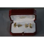 A red leather cased pair of vintage Cartier 18 carat three colour gold ridged design cufflinks.