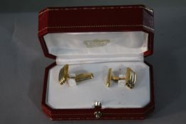 A red leather cased pair of vintage Cartier 18 carat three colour gold ridged design cufflinks.