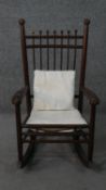 An Arts & Crafts stained wood child's rocking chair, with turned spheres to the top of the spindle