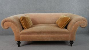 A Chesterfield style two seater sofa, with scrolling arms, upholstered in patterned fabric, on