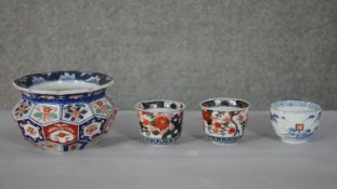 A large Imari style ceramic faceted bowl along with three tea bowls, one with a mountain landscape