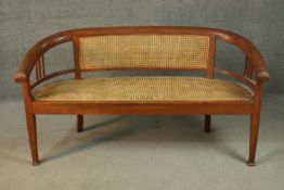 An Edwardian style teak bench, with a caned back and seat, on square section tapering legs with