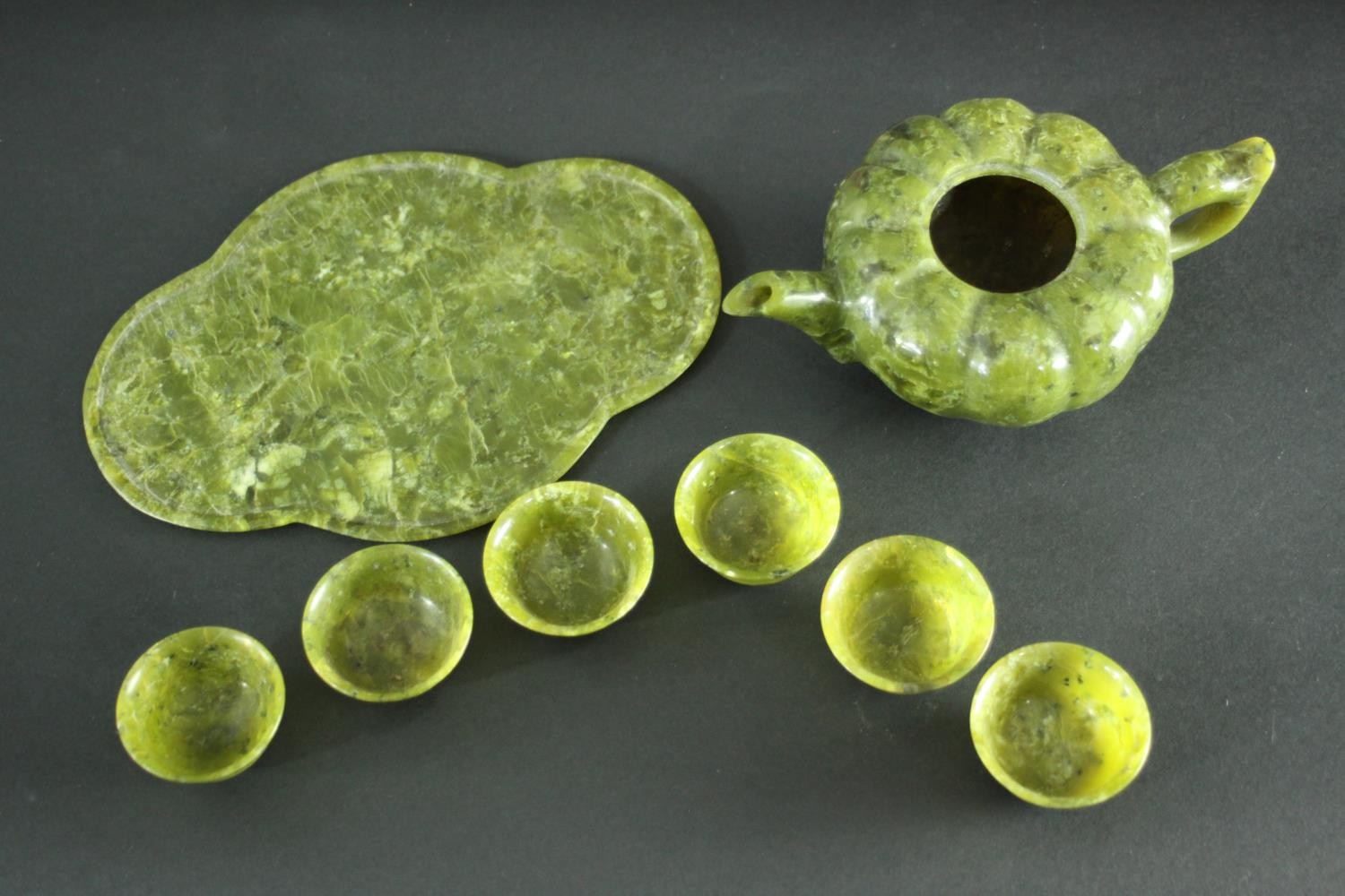 A carved Spinach Jade Chinese tea set. The tea pot (lid missing) of gourd formation with leaf shaped