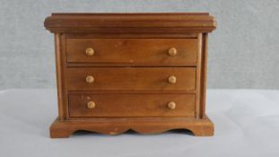 A fruitwood apprentice piece chest of three long drawers with turned handles, on a shaped plinth