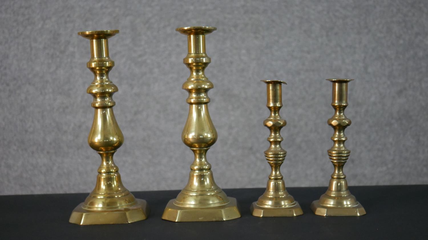 Two pairs of early 20th century brass candle sticks, one set with octagonal bases. H.27.5 W.11.5 D.
