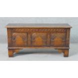 A 17th century style oak coffer, the carved front with faux panels, the feet with shaped brackets.