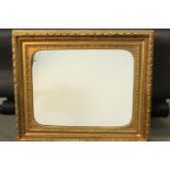 An early 20th century carved giltwood and gesso framed wall mirror. The frame decorated with